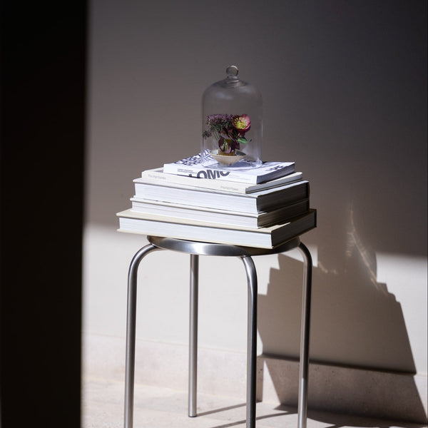 Fanal de vidrio sobre libros en un piso metálico
