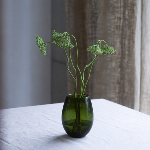 Florero de vidrio verde con ramas